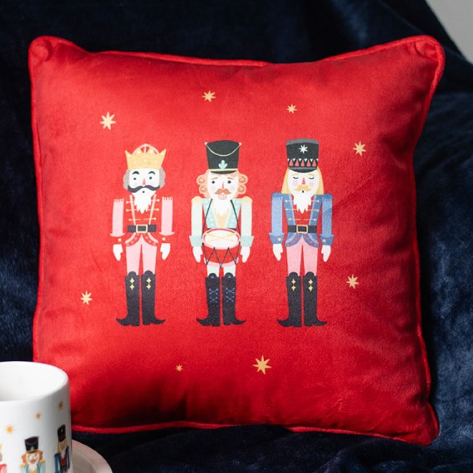 Red square christmas cushion with a trio of traditional nutcrackers and golden star embellishments. 