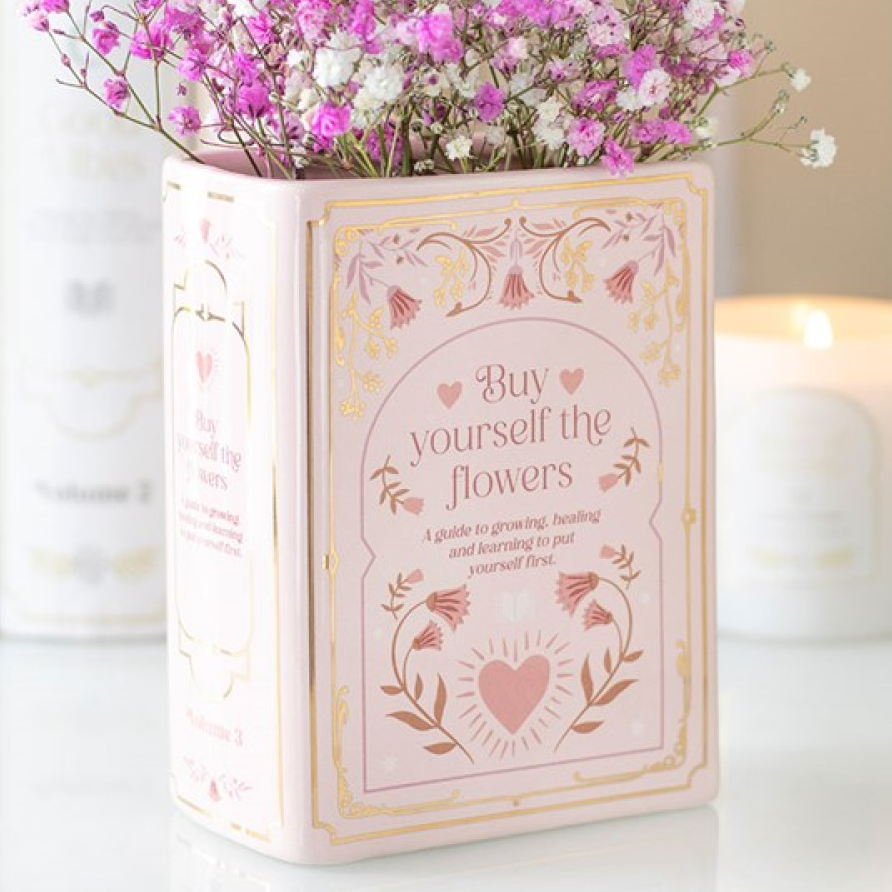 Pink book shaped flower vase with romance themed accents and 'Buy Yourself The Flowers' text.