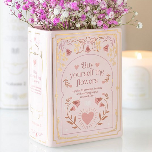 Pink book shaped flower vase with romance themed accents and 'Buy Yourself The Flowers' text.