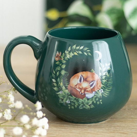 Green rounded ceramic mug with a charming sleeping fox nestled in the forest design. 