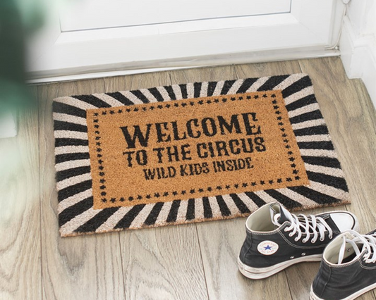 Decorative doormat with 'Welcome to the Circus, Wild Kids Inside' text and a monochrome striped border.